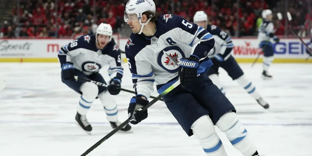 Winnipeg Jets players celebrating a goal with fans cheering in the background at Bell MTS Place.
