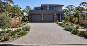 Modern exposed aggregate concrete driveway leading to a double garage in Australia