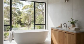 White freestanding oval bath in a bright modern Australian bathroom with timber vanity