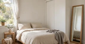 Small Australian bedroom with light neutral walls, queen bed and built-in sliding door wardrobe