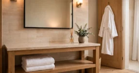 Hotel-style bathroom ideas: calm white Australian bathroom with thick towels, bathrobe on a door hook and warm light