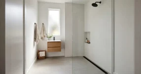 Curbless walk-in shower with frameless glass panel and linear drain in a small Australian bathroom
